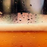 a close up of a glass of beer with drops of water